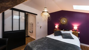 A bedroom with a bed, two bedside lamps, a wall-mounted mirror, and a ceiling light fixture.