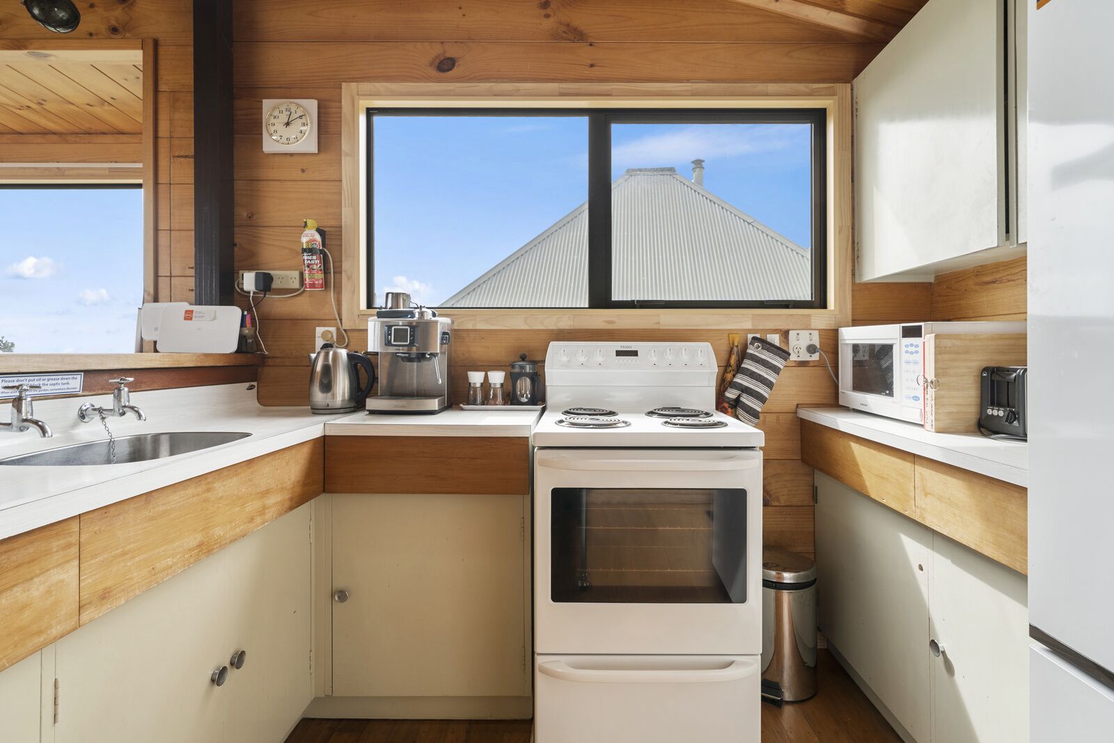 A compact kitchen with a stove, microwave, and sink.