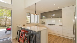 Une cuisine moderne dotée d’un grand îlot central, de tabourets de bar et offrant une vue sur l’extérieur.