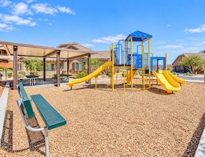 A playground with a slide and climbing structures, surrounded by a covered seating area and a building in the background. - Golden golf course views & pools (Washington)