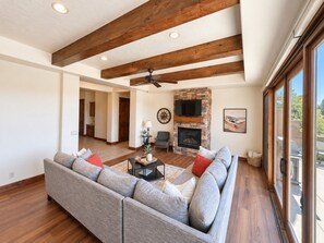 A spacious living room with a sectional sofa, a fireplace, and a large window.