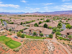 A residential area with multiple houses, green lawns, and a desert landscape in the background. - Golden golf course views & pools (Washington)