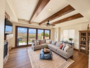 A spacious living room with a large sectional sofa, a fireplace, and a view of the outdoors.