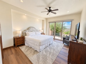 A bedroom with a bed, nightstands, a ceiling fan, a TV, and a view of the outdoors. - Golden golf course views & pools (Washington)