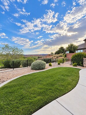 A well-maintained lawn with a curved pathway leading to a house with a stone facade. - Golden golf course views & pools (Washington)