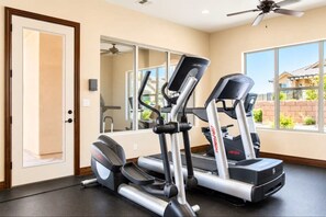 Un gimnasio en casa con dos cintas de correr, una bicicleta estática y un espejo.