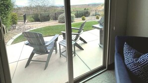 Une pièce dotée d’une porte-fenêtre coulissante qui donne sur un patio extérieur, où se trouvent deux fauteuils Adirondack et une table.