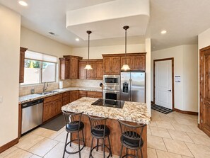 A modern kitchen with wooden cabinets, stainless steel appliances, and a granite countertop. - Golden golf course views & pools (Washington)