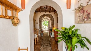 Un pasillo con un arco rústico, muebles de madera y una planta en maceta.
