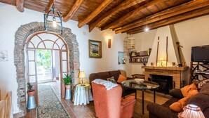 Una sala de estar acogedora con chimenea, un arco de piedra y una estantería.
