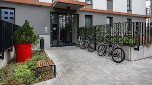 A modern building with a glass door entrance, a red planter, and bicycles parked outside.