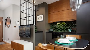 A modern kitchen with wooden cabinets, a green tiled backsplash, and a dining area with a round table and chairs.