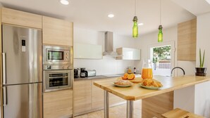 A modern kitchen with stainless steel appliances, a wooden countertop, and a view of the outdoors.