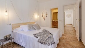 A bedroom with a bed, bedside table, wall-mounted light, and a dreamcatcher.