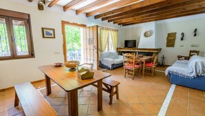 A cozy living room with a wooden table, a sofa, and a TV. - Los Linarejos Ronda by Ruralidays (Málaga)