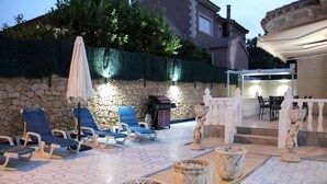 An outdoor patio with lounge chairs, a stone wall, and decorative urns.