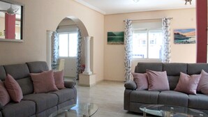 A living room with two grey sofas, a glass coffee table, and a ceiling fan.