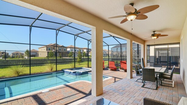 A covered outdoor area with a pool, patio furniture, and a view of neighboring houses. - Cool Breeze by VillaDirect (Davenport)