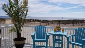 A balcony with two blue chairs and a table, a potted plant, and a view of the beach and ocean. - 4 br townhouse ocean front, at 47th St, has outdoor pool! Lovely, with multiple oceanfront decks. (Ocean City)