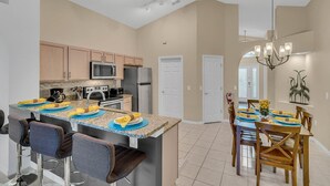 A modern kitchen with granite countertops, stainless steel appliances, and a central island with bar seating. - Disney Backstage Villa by VillaDirect (Kissimmee)