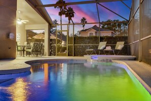 Une piscine avec vue sur le coucher de soleil, des chaises longues et un espace patio.