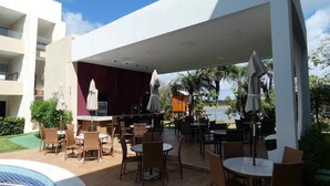 Un'area patio esterna con tavoli e sedie, una piscina e vista sull'acqua.