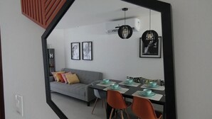 Zona pranzo con tavolo apparecchiato per quattro persone, divano con cuscini e quadri alle pareti.