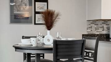 A dining area with a round table, chairs, a ceiling fan, and framed pictures on the wall.