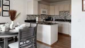 A modern kitchen with white cabinets, a central island, and a dining area with a table set for four.
