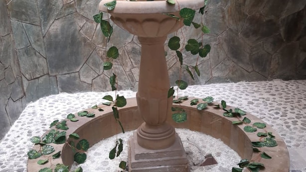 A stone fountain with a circular basin and ivy plants. - Rincon de Granada (Cali)