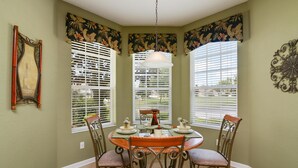 A dining area with a round table, chairs, and a hanging light fixture.