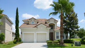 A two-story house with a tiled roof, a garage, and a well-maintained lawn.