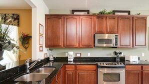 A kitchen with wooden cabinets, stainless steel appliances, and a granite countertop.