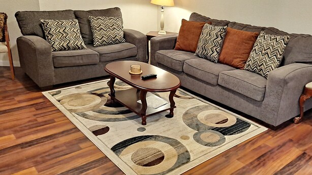 A living room with two grey sofas, a wooden coffee table, and a patterned rug. - Beautiful place for staying (Aurora)