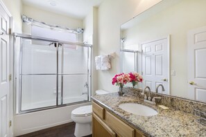 A bathroom with a shower, toilet, sink, and a large mirror. - Fantasy Villa by VillaDirect (Kissimmee)
