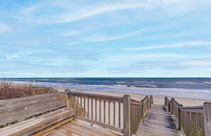 A wooden boardwalk leading to a beach with waves crashing onto the shore.