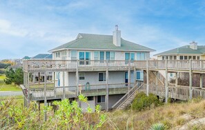 A two-story house with a balcony, a chimney, and a wooden deck.