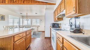 Une cuisine avec des meubles en bois, un grand îlot central, un four à micro-ondes, une cuisinière et un évier.