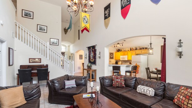 A spacious living area with leather sofas, a wooden coffee table, and a red rug. A staircase leads to another level. - Harrys Hide Out by VillaDirect (Kissimmee)