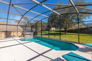 A swimming pool with a covered area, lounge chairs, and a view of the surrounding landscape. - Harrys Hide Out by VillaDirect (Kissimmee)