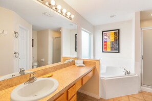A bathroom with a sink, mirror, vanity, and bathtub. - Harrys Hide Out by VillaDirect (Kissimmee)