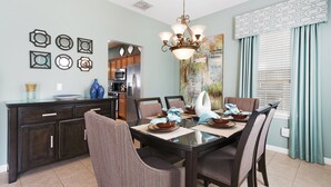 A dining area with a dark wooden table, cushioned chairs, and a chandelier. - Mickey Haven by VillaDirect (Kissimmee)
