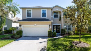 A two-story house with a garage, a well-maintained lawn, and a small tree in the front yard. - Mickey Haven by VillaDirect (Kissimmee)