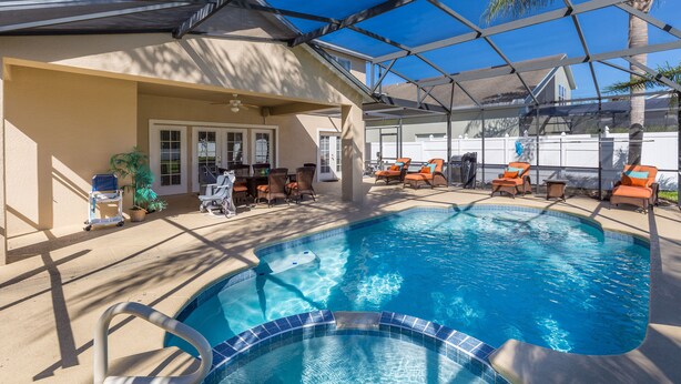 A swimming pool with a covered area, lounge chairs, and a small table. - Mickey Haven by VillaDirect (Kissimmee)