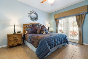 A bedroom with a bed, nightstands, a mirror, and a view through a window.