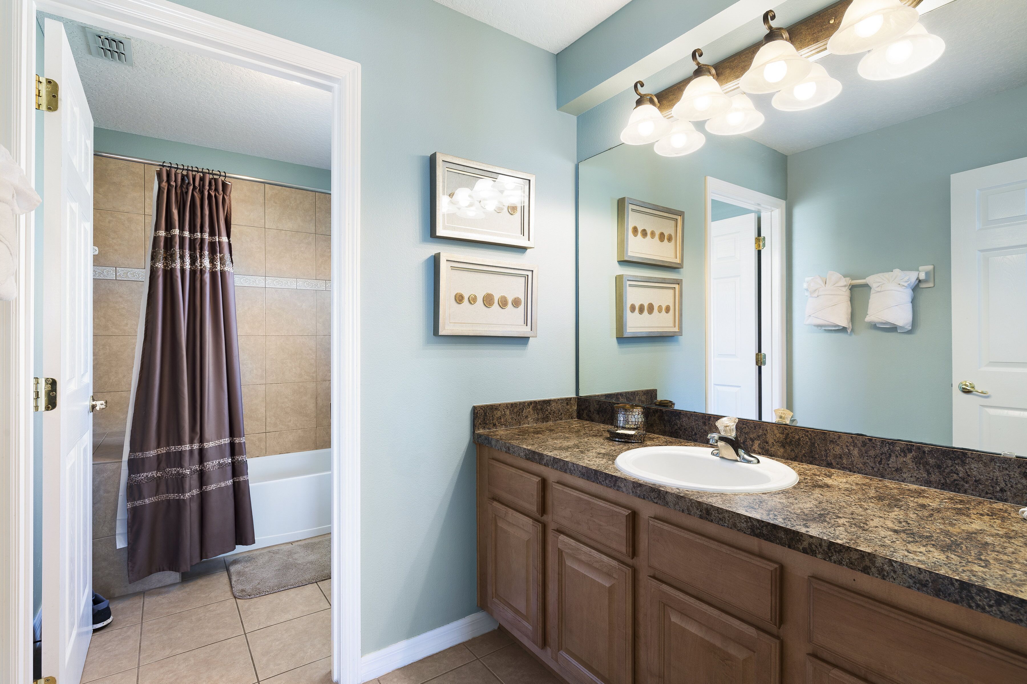 A bathroom with a sink, vanity, and a shower curtain.