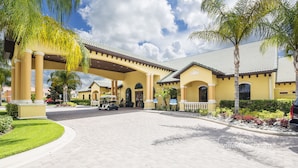 A hotel entrance with a covered walkway, palm trees, and a paved driveway. - Paradise Getaway by VillaDirect (Kissimmee)