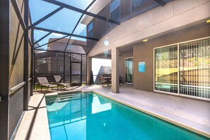 Ett modernt inomhuspoolområde med väggar av genomskinligt glas, en pool och solstolar.