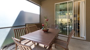 A balcony with a wooden table and chairs, a potted plant, and a sliding glass door. - Paradise Getaway by VillaDirect (Kissimmee)