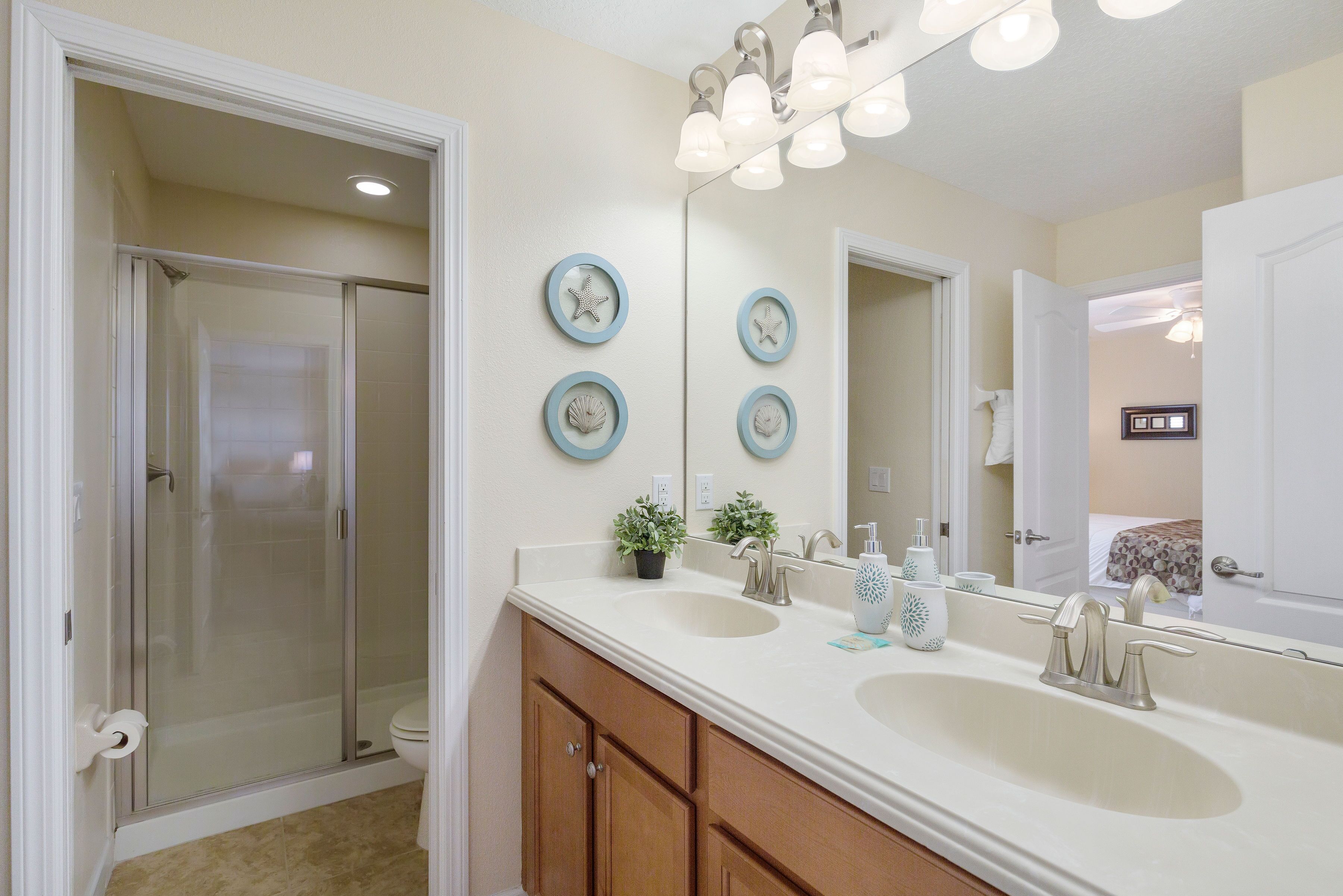 A bathroom with a glass-enclosed shower, two sinks, and a large mirror.